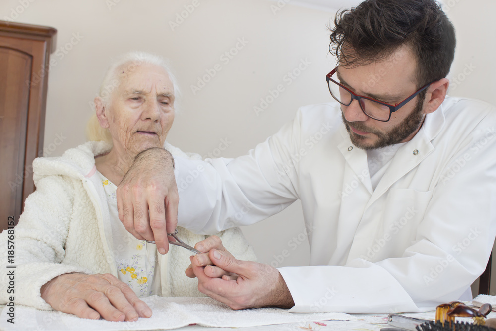 Pielęgniarz obcina paznokcie u rąk starej kobiety. - obrazy, fototapety, plakaty 