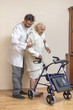 Pielęgniarz pomaga staruszce przy chodzeniu przy pomocy chodzika, balkonika.