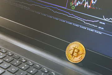 Bitcoin coin placed on modern black notebook . Close-Up photo Bitcoin , exchange virtual value, crypto digital money . Background Live Stock trading through internet .Selling big amounts, real estate.