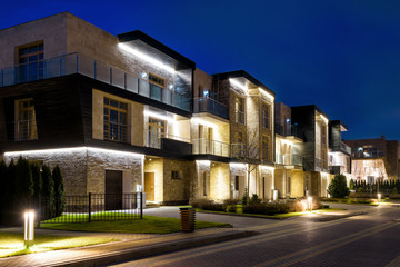 Townhouses with modern lights in night town, contemporary design