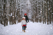 © alexkich - A winter fairy tale, a young mother and her daughter ride a sled