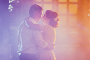 bride and groom dancing the first dance in the blurry background