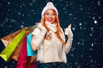 Wall Mural - Christmas and New Year holidays.. Shopping woman holding color bags and on winter background with snow in black friday. Sale poster with copy space. Thumbs up.