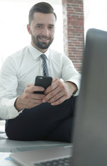 Canvas Print - businessman holding a smartphone and looking at the camera