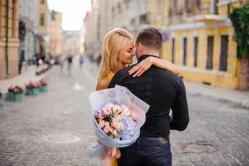 Poster - Young and beautiful blonde woman holding a bouquet of flowers and hugging a man