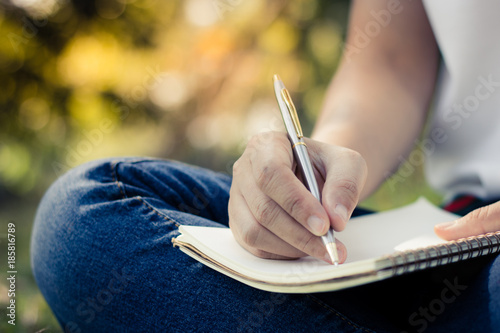 Cuadros en Lienzo close up young women writing on notebook in park, concept in education and knowledge