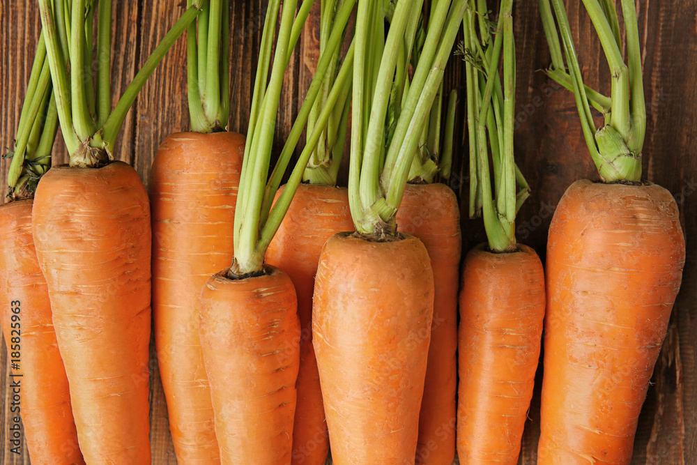 Tasty ripe carrots on wooden background