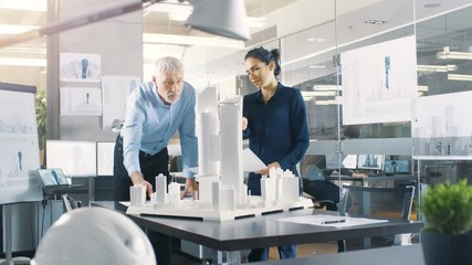 Poster - Chief Male Architect and Female Engineer Work with City Buildings Model. Bright People Work as Urban Planners. Shot on RED EPIC-W 8K Helium Cinema Camera.