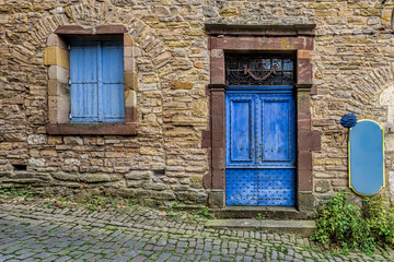 Wall Mural - Pale blue and worn door and windows  on the stone walls of a sma