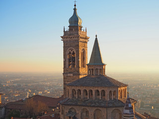 Bergamo, Italy. The old city. Aerial view of the Basilica of Santa Maria Maggiore and the chapel Colleoni during the sunset. In the background the Po plain