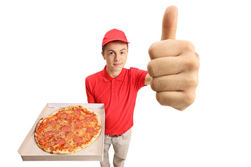 Wall Mural - Teenage pizza delivery boy holding a pizza and making a thumb up gesture