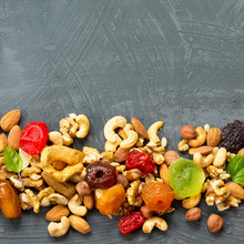 Various Dried Fruits And Mix Nuts On A Gray Stone Or Slate Background.  The Concept Of The Jewish Holiday Tu Bishvat. Flat Lay, Top View With Copy Space.