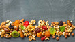 © elena_hramowa - Various dried fruits and mix nuts on a gray stone or slate background.  The concept of the Jewish holiday Tu Bishvat. Flat lay, top view with copy space.