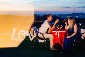 lovers drink wine on the roof of the building against the backgr