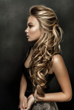 Fototapeta  - Beautiful girl with long wavy hair. fair-haired model with curly hairstyle and fashionable makeup