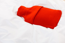 Warm Red Hot Water Bottle On White Bedding