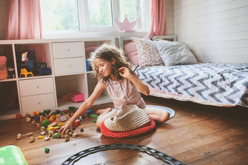 child girl cleaning her room and organize wooden toys into knitted storage bag. housework and help c