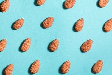 Symmetrical pattern of almonds on blue. Flat lay.