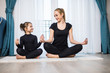 © F8  \ Suport Ukraine - Beautiful young woman and her charming little daughter are smiling while doing yoga together at home