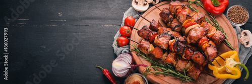 Cuadros en Lienzo Shish kebab on skewers with onions. On the black wooden table.