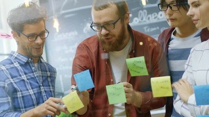 Poster - Diverse Team of Young Developers Brainstorming, They Have Discussion and Use Glass Board and Sticky Papers to Conceptualize Their New Plan. Shot on RED EPIC-W 8K Helium Cinema Camera.