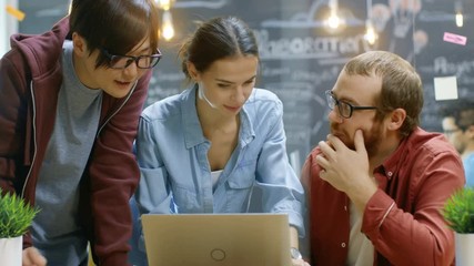 Poster - Three Creative People Have Active Discussion While Using Laptop. Stylish Young People Work in Trendy Environment. Shot on RED EPIC-W 8K Helium Cinema Camera.