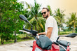 © zulman - Brutal man sitting on his motorcycle on palm background