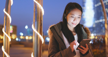 Poster - Young woman using smart phone in the city at night, urban cityscape background