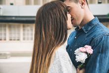 Young Beautiful In Love Couple Hugging Each Other In The Middle Of The Street In A Romantic Way With Flowers