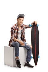 Wall Mural - Teenage hipster with a longboard sitting on a cube