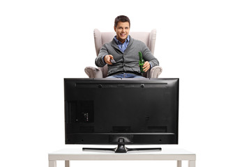 Sticker - Young guy with a remote control and a bottle of beer sitting in an armchair and watching television