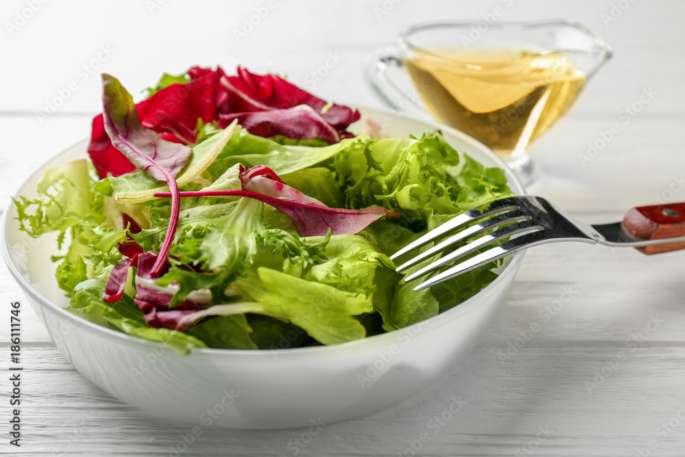 Plate with fresh salad on white wooden table