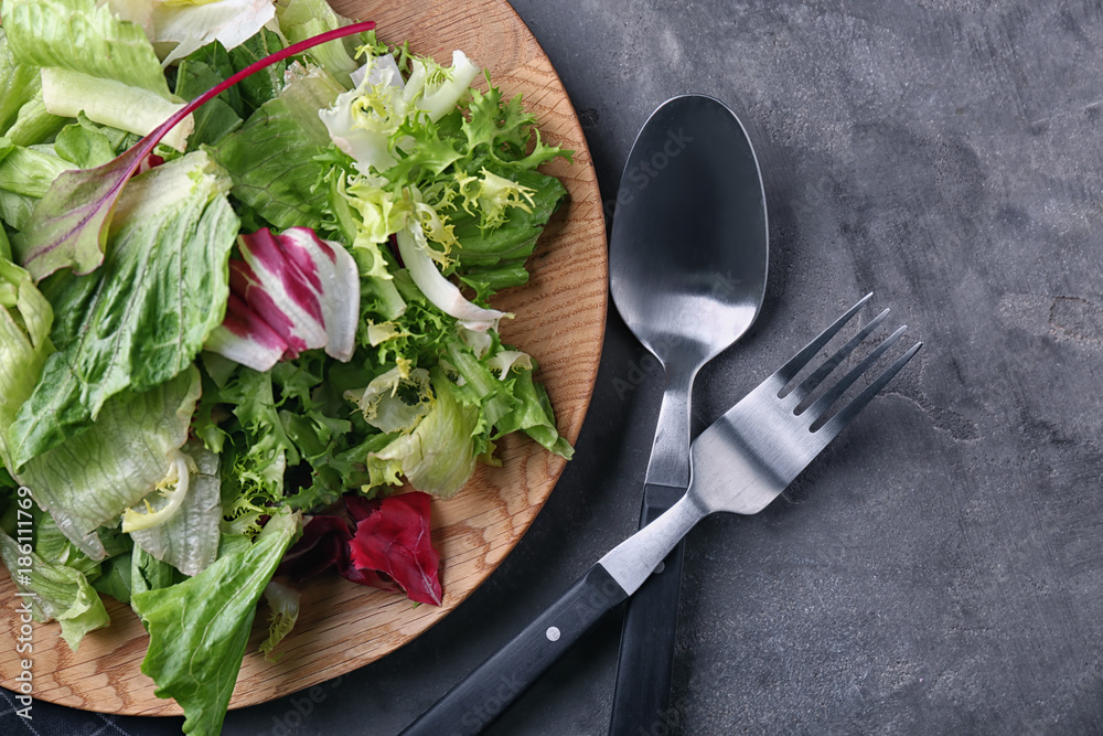 Plate with fresh salad on grey table, top view