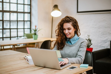 successful young woman in modern office working on laptop.