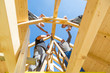 Roof builders mounting prefabricated wooden roof construction. Construction industry concept.