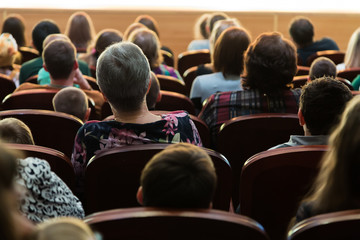 People, parents with children in the audience watching a children's show. Sold out. Shooting from the back.