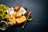 Fototapeta Dmuchawce - Assortment of cheeses, a bottle of wine, honey, nuts and spices, on a wooden table. Top view. Free space for text.