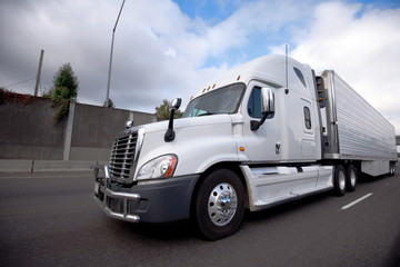 Big rig semi truck with reefer unit on refrigerator trailer running on the highway