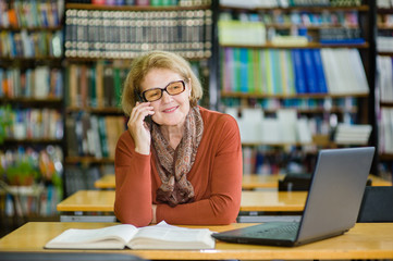 Wall Mural - senior woman using mobile phone in library