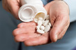 © O.Farion - Woman hand holds white medication pills, pours from a white bottle into palm the calcium tablets dietary supplement