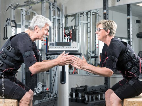 Fotografia, Obraz Pärchen im mittleren alter trainiert im Fitnessstudio mit einem EMS Gerät Stromi