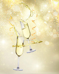 Wall Mural - Two festive champagne glasses with streaming paper on golden bokeh background with lights