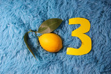Fototapeta  - The third month of pregnancy. Fetus is a child the size of a lemon. Lemon on a blue background. The figure is three yellow.
