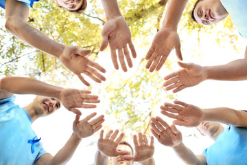 Sticker - Young men in t-shirts with blue ribbons making circle with their hands outdoors. Prostate cancer awareness concept