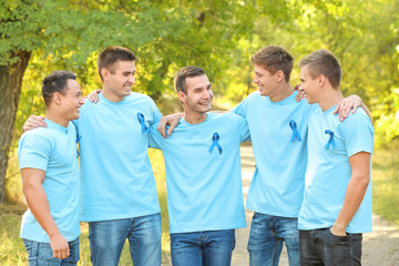 Wall Mural - Young men in t-shirts with blue ribbons outdoors. Prostate cancer awareness concept