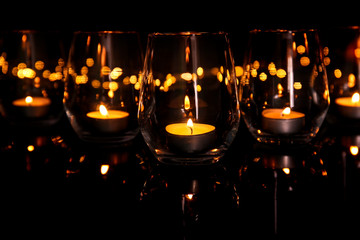 Wall Mural - Glasses with burning candles on dark background