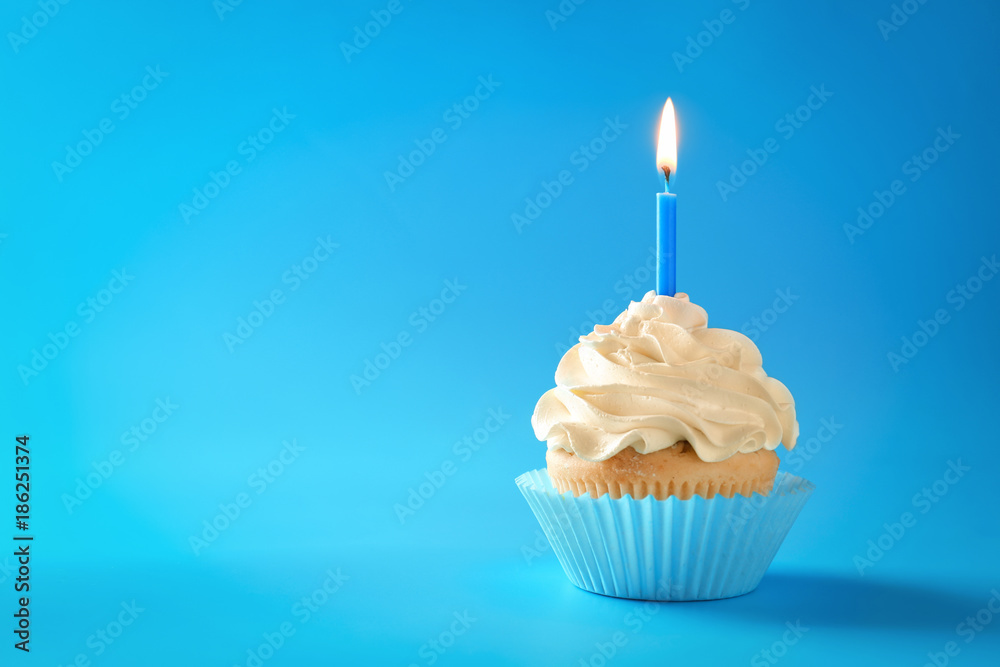 Tasty cupcake with candle on color background