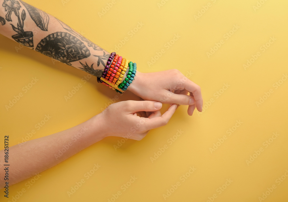 Woman with rainbow bracelet on color background, top view