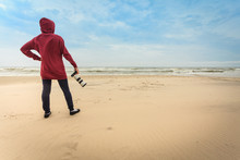 Woman Walking On Beach With Camera