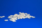 Fototapeta  - Tablets with calcium on a blue background. White pills on a colored background.